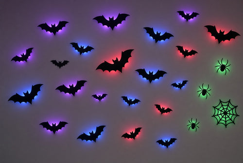 Mur avec chauves-souris noires rétroéclairées en violet, bleu et rouge, et araignées avec toile en vert